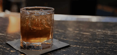 Drink with ice on a coaster at a bar
