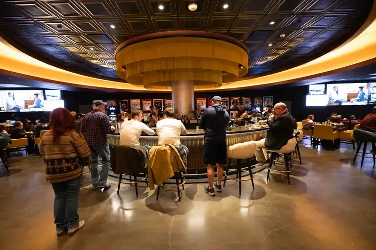 People socialize around circular bar in bustling venue
