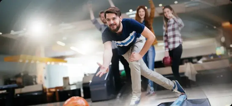 Man bowling while friends cheer in background