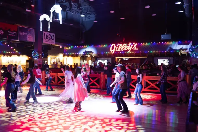 People dancing at lively Gilleys saloon under colorful lights