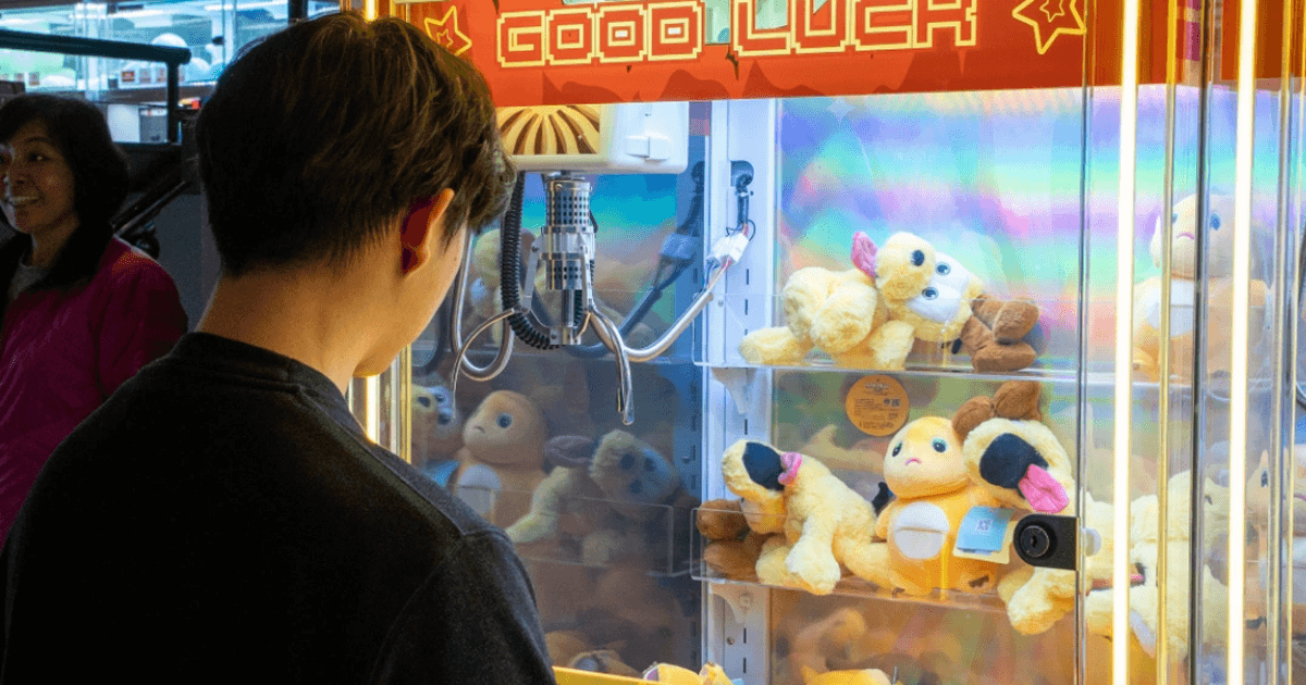 Person playing a claw machine at Gilley's Hi-Score Arcade